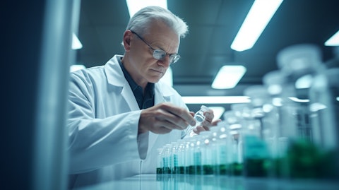 A scientist in a lab coat observing a line of medicine pills in a container.