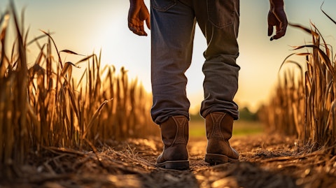 A farmer standing in a sun-drenched field wearing overalls and a rugged pair of western-style boots.