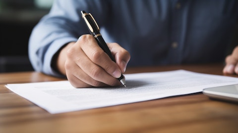 A close-up of a hand signing a title insurance document over a wooden table.