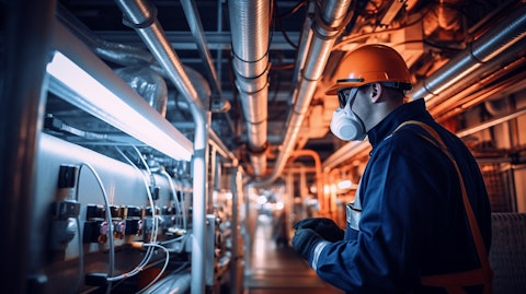 A technician in a boiler suit working on an industrial air conditioning system inside a factory.