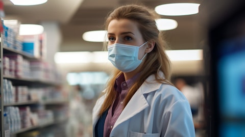 A pharmacist wearing a white lab coat and a face mask dispenses biosimilars at a pharmacy.