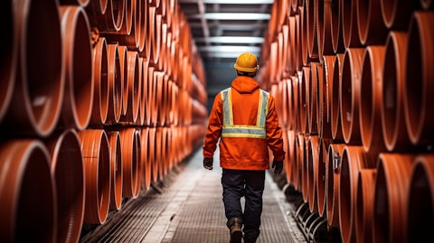 A worker in a hardhat walking down a corridor lined with thermoplastic corrugated pipes.