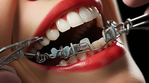 A close-up of a dental bracket and wires being fitted into a patient’s mouth.