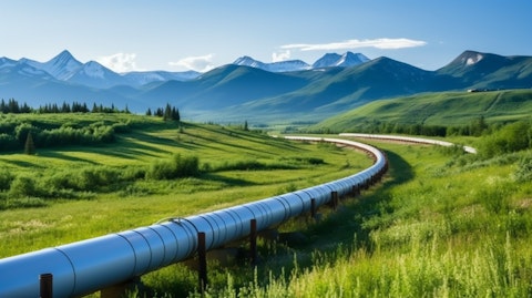 A large natural gas pipeline running through a rural landscape with mountains in the background.
