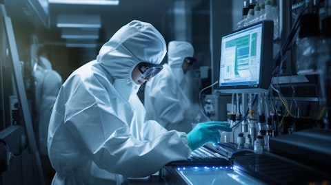 A scientist in a laboratory wearing safety gear while operating a mass spectrometry machine.