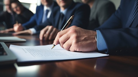 A close-up of hands signing a contract at a boardroom table to shareholders. 
