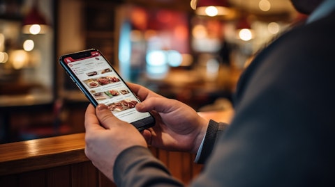 A close-up of a person using a mobile device in a restaurant, using the Yelps Reservations feature.