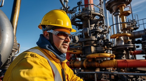 A worker in protective gear near a large natural gas exploration machinery.