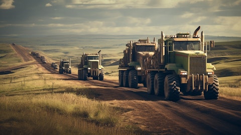 A convoy of industrial trucks loaded with heavy equipment rolling through a rural landscape.