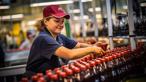 A woman pouring a freshly made beverage from a large-scale bottling line.