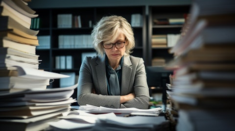 A finance executive in her office analyzing a stack of documents.