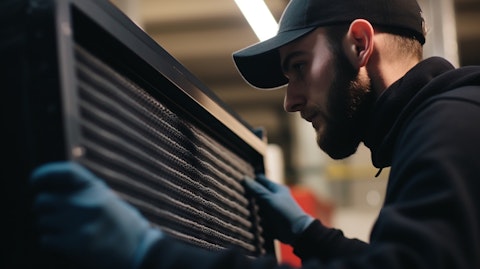 A close-up of a factory worker carefully installing a part on an air filtration system.