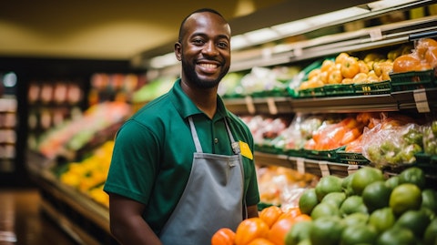 A grocery store employee stocking shelves with fresh fruits and vegetables.