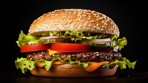 A closeup of a juicy hamburger sandwich with tomatoes and lettuce, on a sesame bun.
