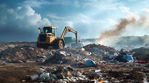 An excavator at a landfill site operating amidst a pile of solid waste.