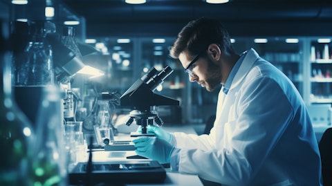 A scientist in a lab coat operating a microscope, looking at a drug candidate.