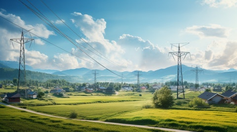 A power line stretching across a sunbathed landscape with rural homes in the foreground.