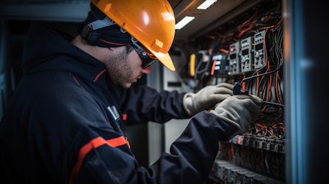 A close-up of a person in personal protective gear wiring up an electrical panel.