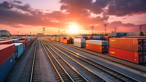 A train loaded with intermodal containers, its tracks winding through an industrial landscape.