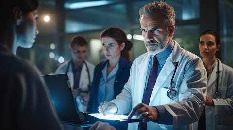 A doctor looking at their computer, discussing their patient's care options with a group of experts.