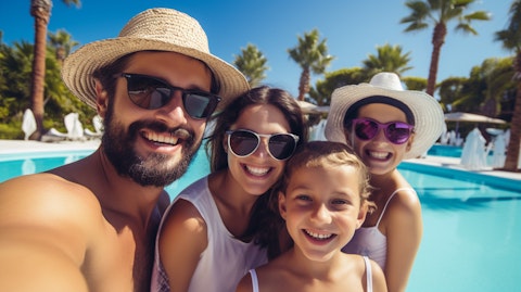 A happy vacationer taking a selfie with their family in front of a grand pool provided by the company.