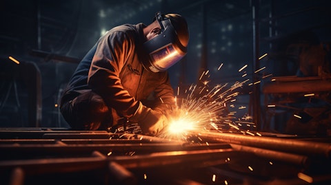 A worker welding an intricate frame in a factory for heavy construction machinery.
