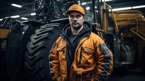An industrial worker in overalls next to a large-scale, custom-designed machine.
