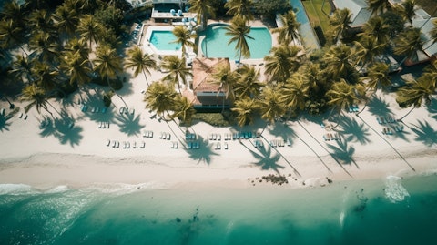 Aerial view of the beachfront resort with a palm tree-lined beach.