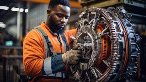 A factory worker in a safety vest tightening a V-belt on a power transmission assembly.