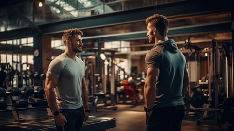 A customer talking to a personal coach while working on their fitness goals in a modern gym.