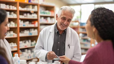 A pharmacist assisting elderly customers with their GoodRX codes at a local pharmacy.