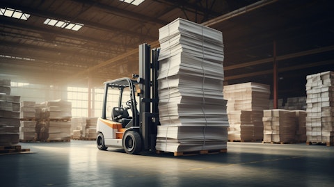 A forklift lifting a large stack of paperboards in a modern warehouse.