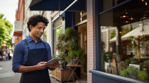 A businessperson standing in front of a brick-and-mortar establishment using a tablet to process an in-person payment.