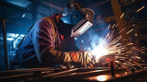 A welder wearing protective gear and goggles, completing a welding job in a modern factory.
