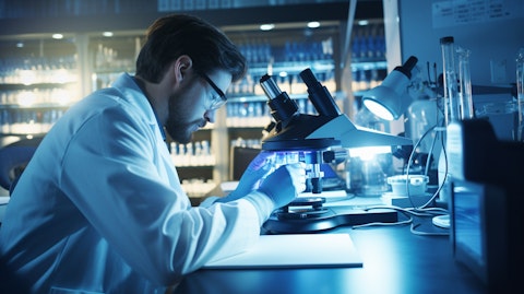 A geneticist in a lab coat using high tech microscopes to research hepatitis B and influenza A viruses.