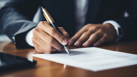 A close up of a man signing off on a loan document, showing the company's commitment to providing financial services.