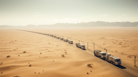 A long convoy of trucks driving across miles of desert, carrying offshore energy services equipment.