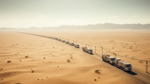 A long convoy of trucks driving across miles of desert, carrying offshore energy services equipment. 