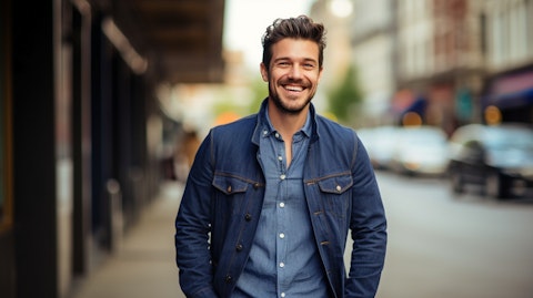 A stylishly dressed man wearing jeans and a jacket from the company, smiling confidently.