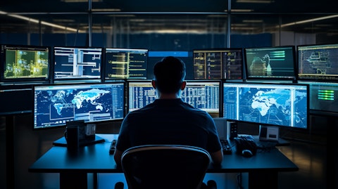A systems administrator sitting at their desk surrounded by computer monitors, overseeing a complex infrastructure.