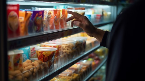 A close-up of a hand selecting a food or beverage item from a store shelf.