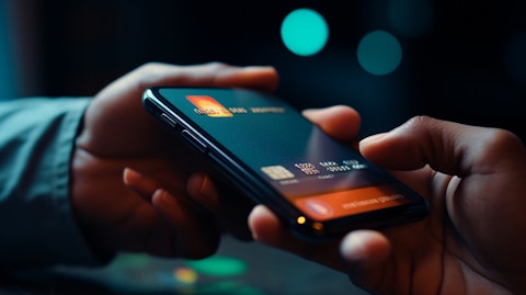 A close-up of a person's hand holding a credit card while using a mobile application to make a payment.