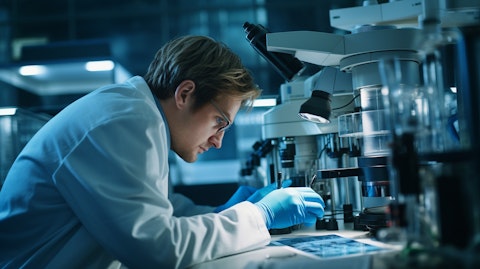 A researcher looking through a microscope at a sample in the lab.
