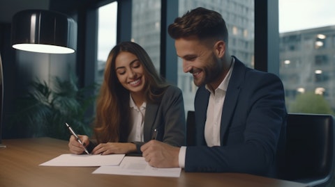 A professional couple smiling while signing a real estate contract in a modern office building.