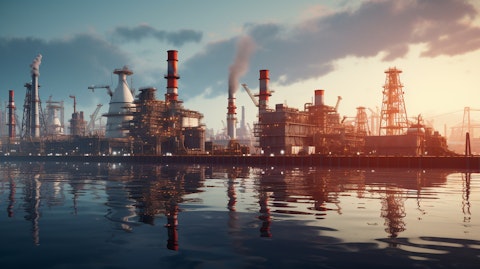 A large oil refinery against a backdrop of ocean containers and industrial cranes.