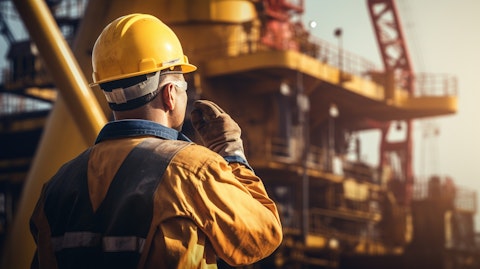 A close-up of a person wearing safety equipment examining an oil well rig.