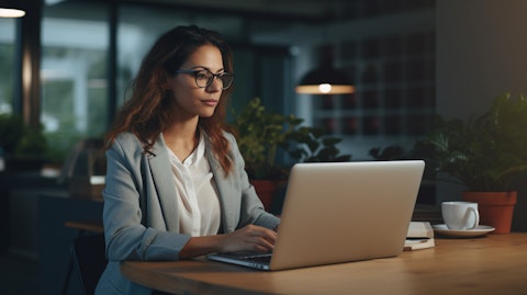 A young professional woman holding a laptop, discussing health insurance plans at her desk.