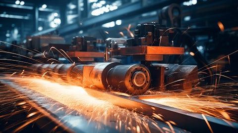 A close-up of industrial machinery used for steel production, the sparks flying off the sides.