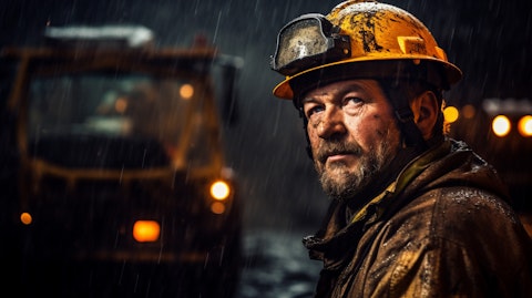A miner deep in a mine with the company's advanced off-the-road equipment in the background.
