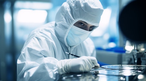 Close-up of a worker wearing protective gear inspecting a silicon wafer in a laboratory.